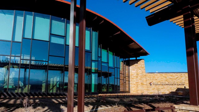 a bank of curved windows with tint form one wall of the Visitor and Research Center