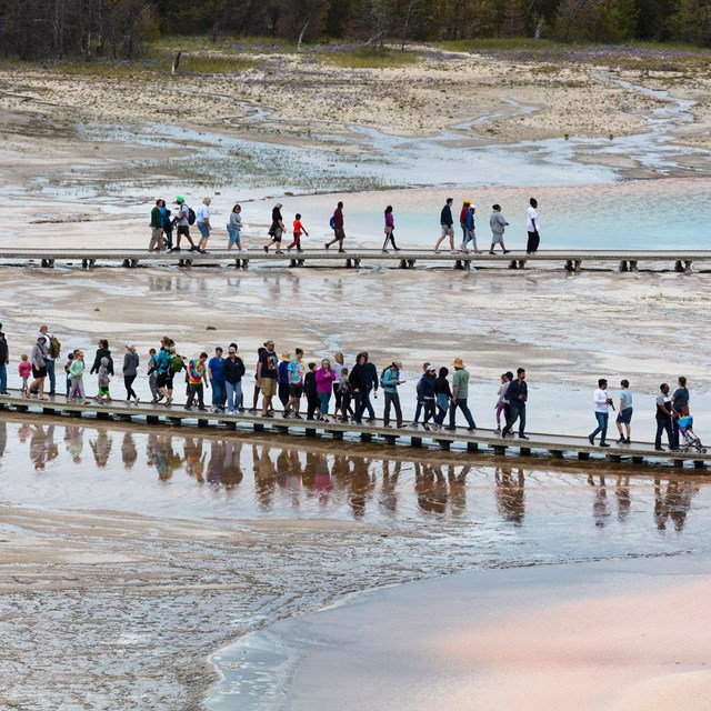 People walking on boardwalks near hot springs