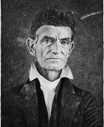 black and white image of John Brown; he's clean shaven; wearing a white collared shirt and dark coat