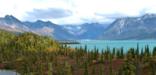 Fall colors dot a landscape with towering mountain peaks and turquoise lakes in Lake Clark National Park and Preserve.